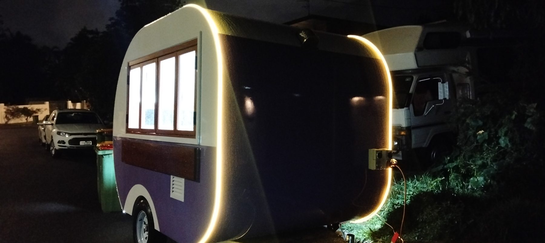 Teardrop trailer with glowing LED edge lighting at night