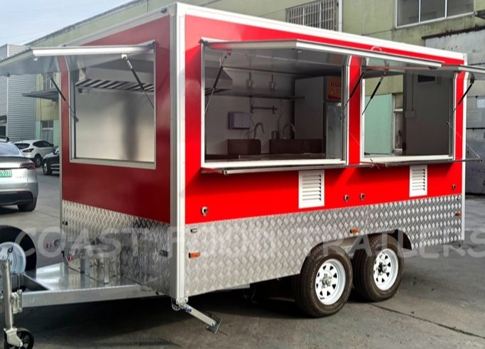 Red food trailer with diamond-plate skirt and two serving windows